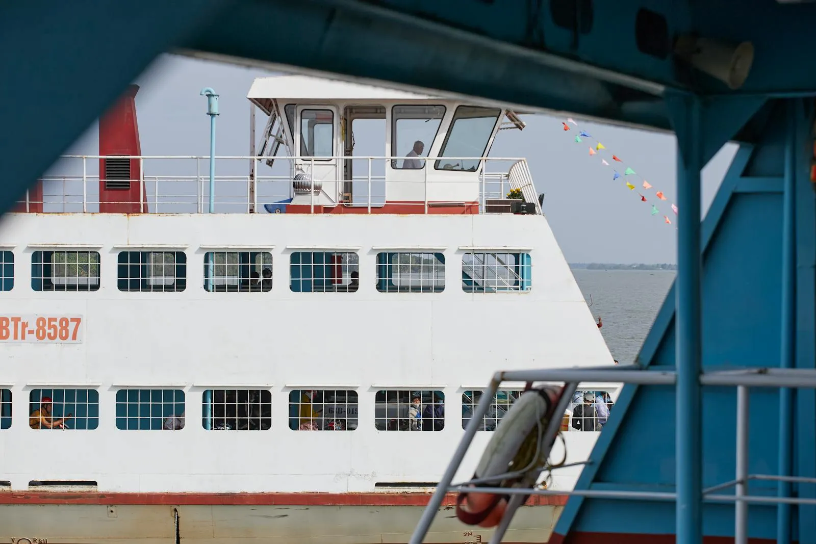 A passenger ferry boat crossing the river in An Hoi, Vinh Long, Vietnam, with colorful flags.