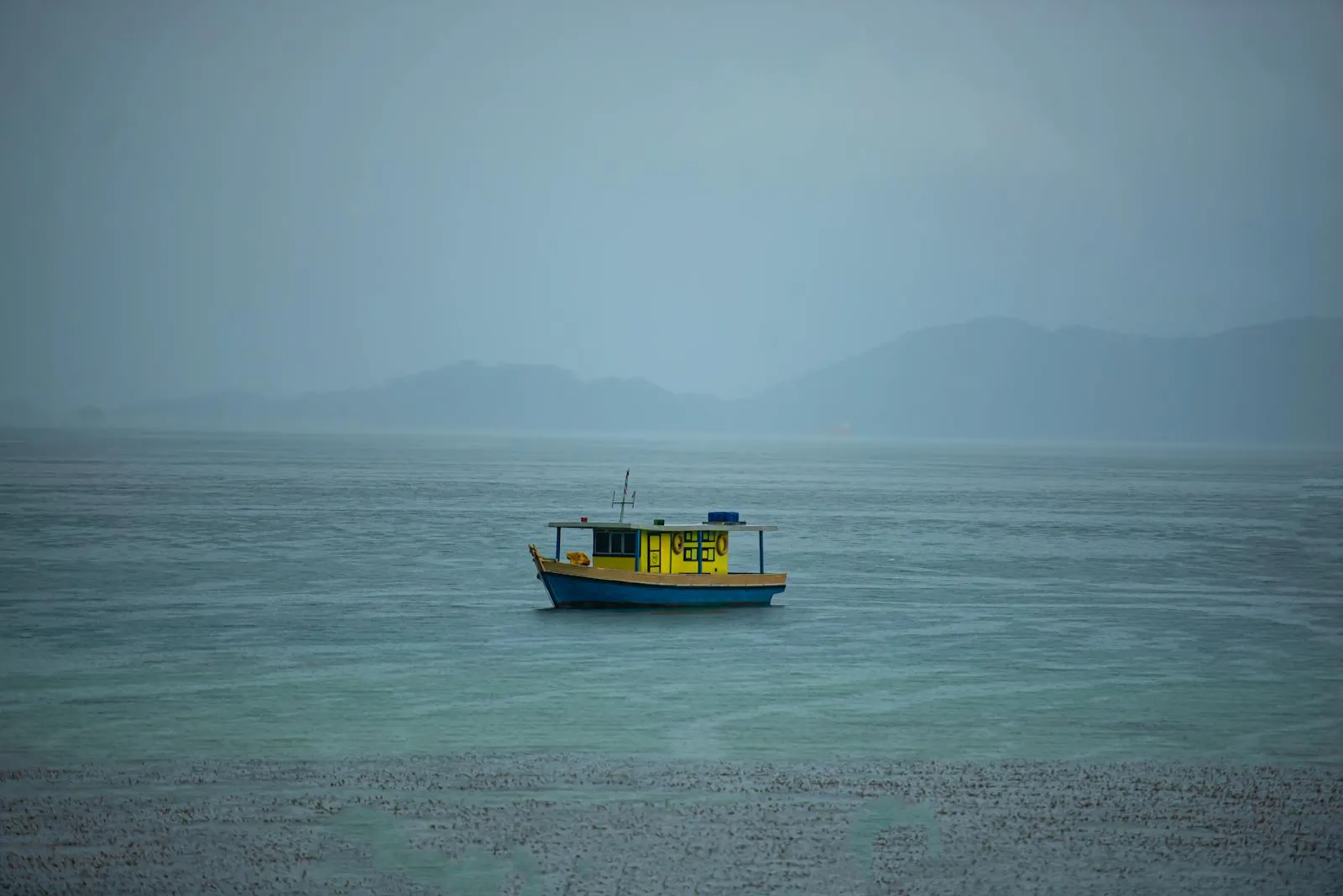 A yellow boat floats on the tranquil sea near Tuaran, Sabah, Malaysia, under a clear sky.