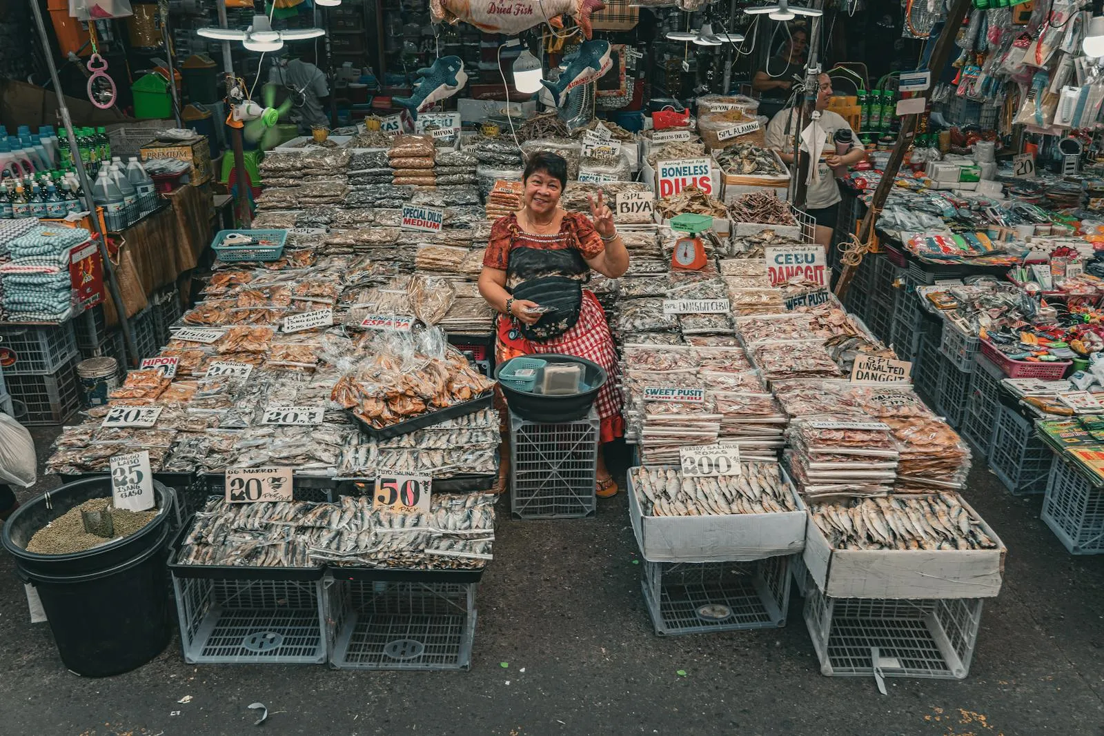 Smiling vendor at a lively fish market in Manila, showcasing a variety of fresh and dried fish.