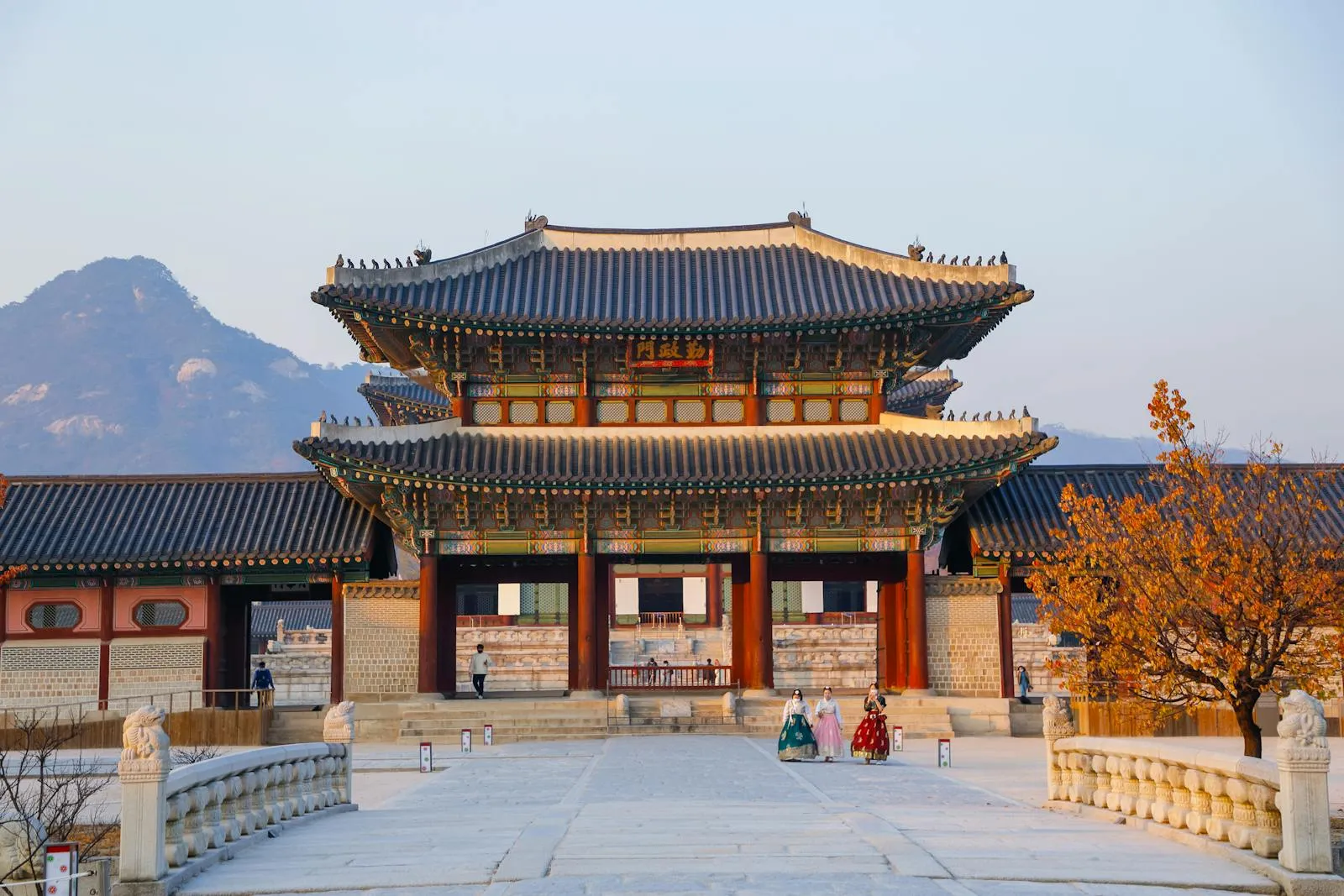 Beautiful view of Gyeongbokgung Palace's traditional architecture with mountains in the background at sunset.