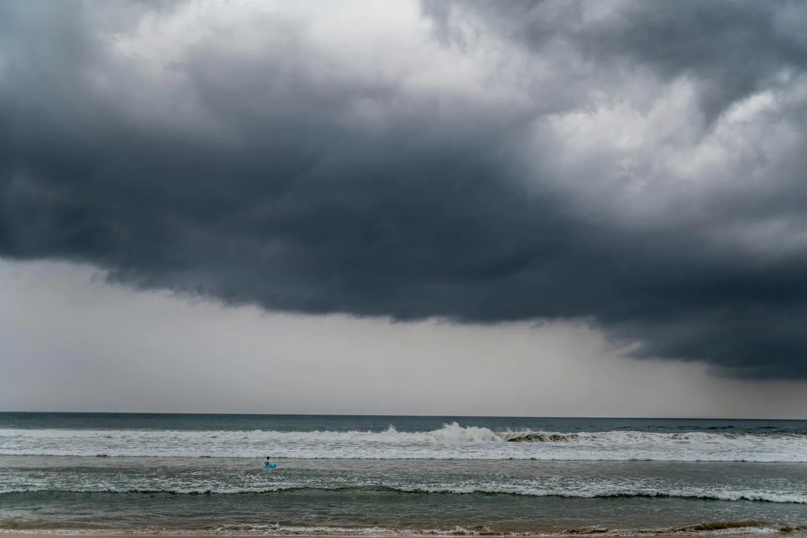 Dark storm clouds hover over waves at Ahangama Beach, Sri Lanka, creating a dramatic seascape.