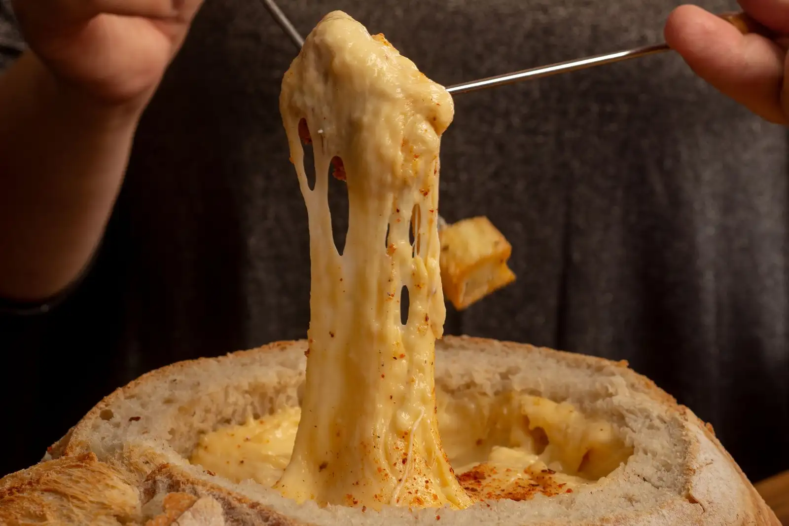 Traditional Swiss cheese fondue in a caquelon pot with bread cubes