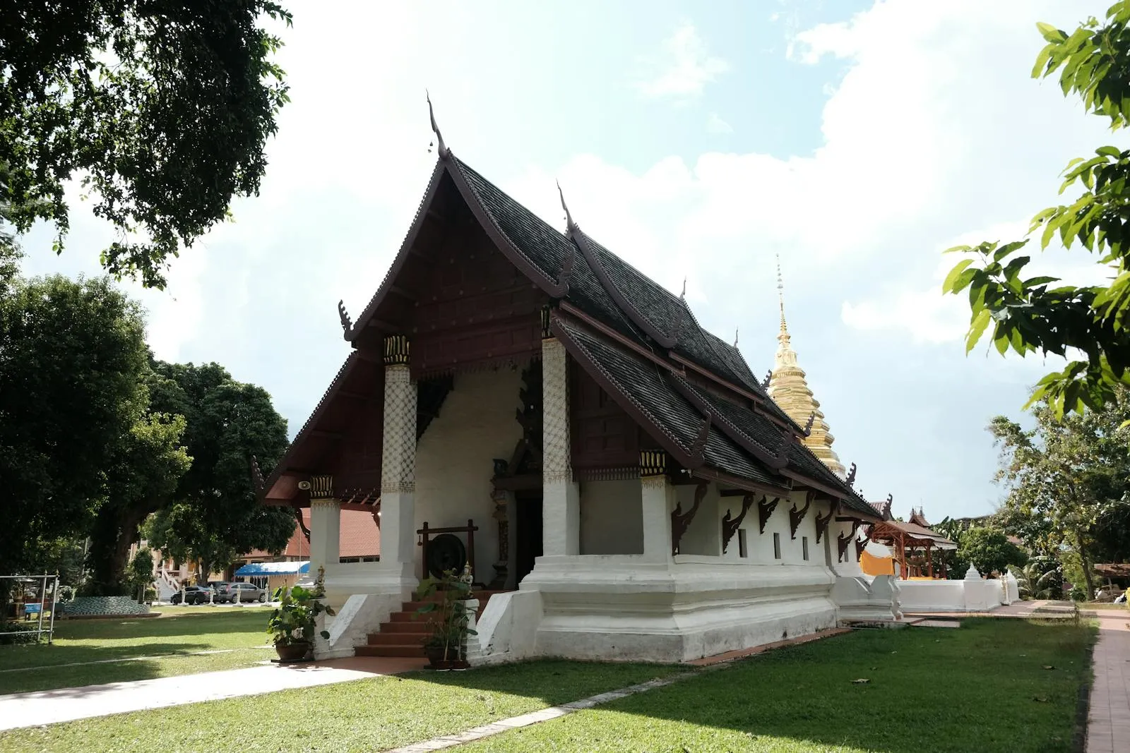 Beautiful Thai temple with traditional architecture amidst lush greenery on a sunny day.